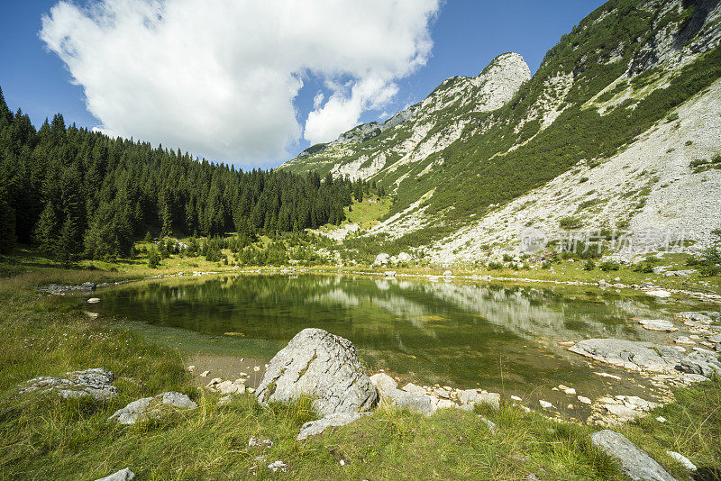 在蓝天下的“Velika Baba”山前，朱利安阿尔卑斯山上的“Dupeljsko jezero”孤独山湖